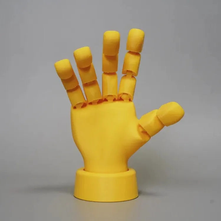 Yellow 3D printed hand prop with movable joints on a plain background.