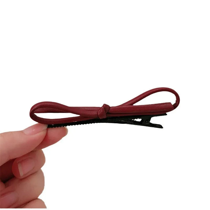 Wine red leather bow barrette hair accessory showing manual craftsmanship and clip mechanism