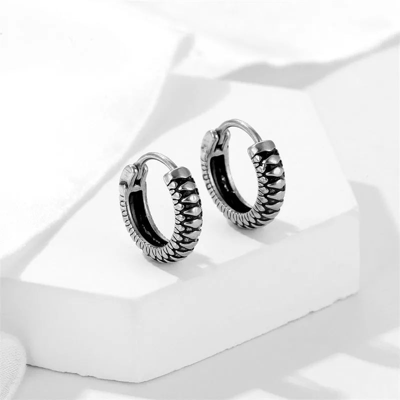 A pair of silver geometric twist earrings on a round base made from stainless steel.
