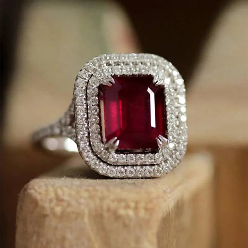 Geometric square copper women's ring with a red rhinestone, shown on a finger.
