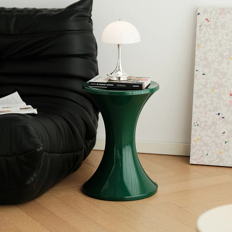 Green plastic hourglass style shoe changing stool on a wooden floor