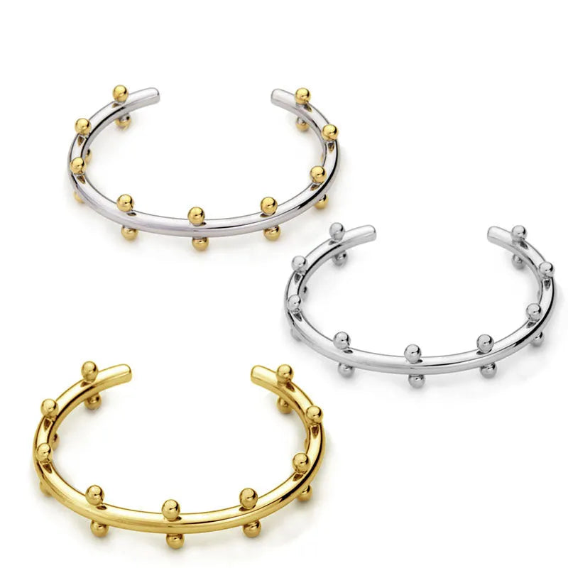 Stainless steel alloy C-shaped bracelet with textured rivet design and bean beads on an adjustable clasp.