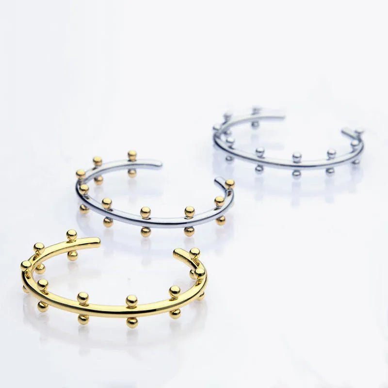 Stainless steel alloy C-shaped bracelet with textured rivet design and bean beads on an adjustable clasp.
