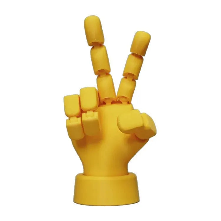 Yellow 3D printed hand prop with movable joints on a plain background.