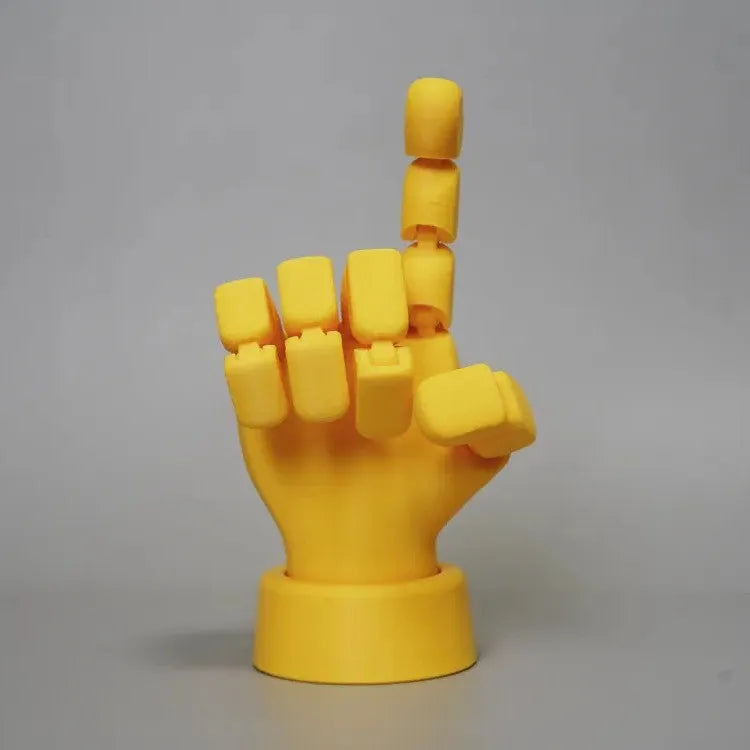 Yellow 3D printed hand prop with movable joints on a plain background.