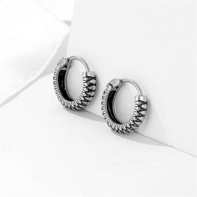 A pair of silver geometric twist earrings on a round base made from stainless steel.
