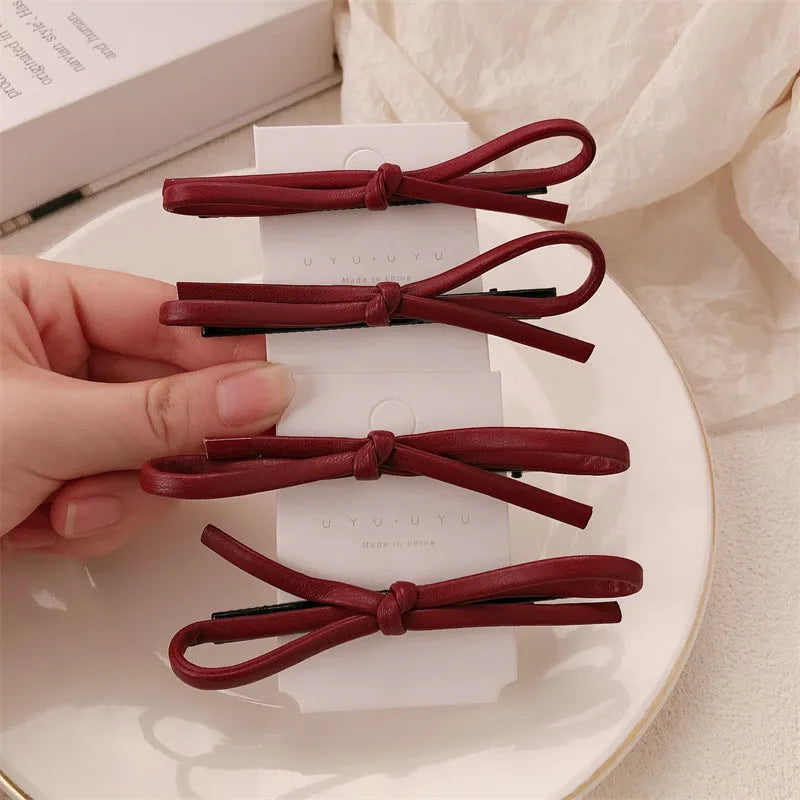 Wine red leather bow barrette hair accessory showing manual craftsmanship and clip mechanism