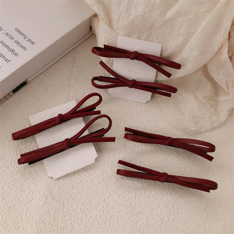 Wine red leather bow barrette hair accessory showing manual craftsmanship and clip mechanism