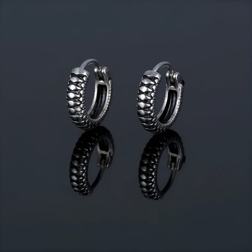 A pair of silver geometric twist earrings on a round base made from stainless steel.