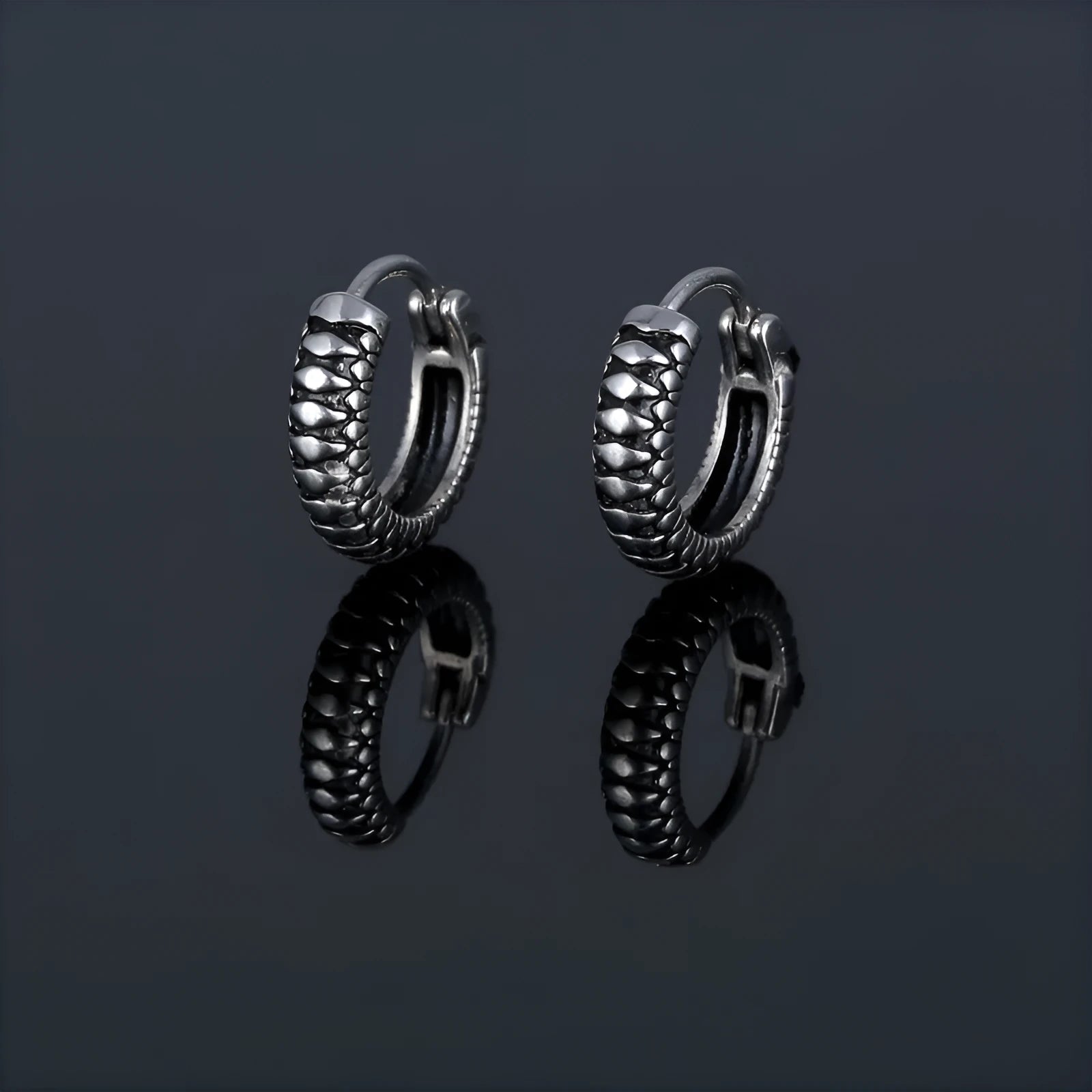 A pair of silver geometric twist earrings on a round base made from stainless steel.