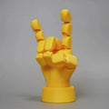 Yellow 3D printed hand prop with movable joints on a plain background.