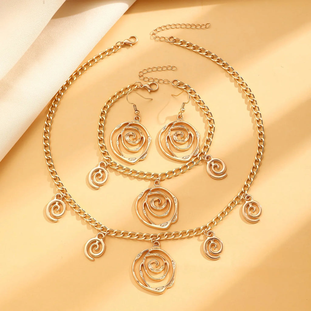 Geometric spiral donut jewellery set with gold necklace, bracelet, and ear hooks on dark background