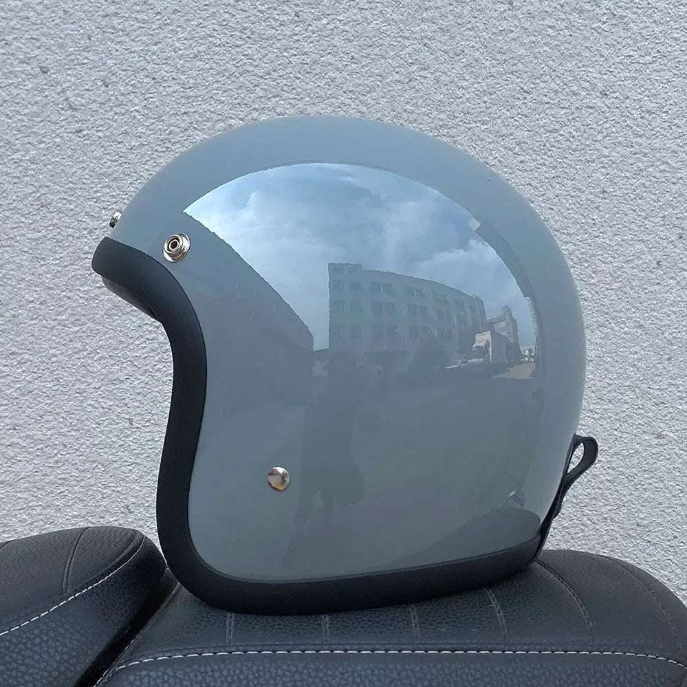 A retro-style motorcycle half helmet made from grey fibreglass, shown from the side.