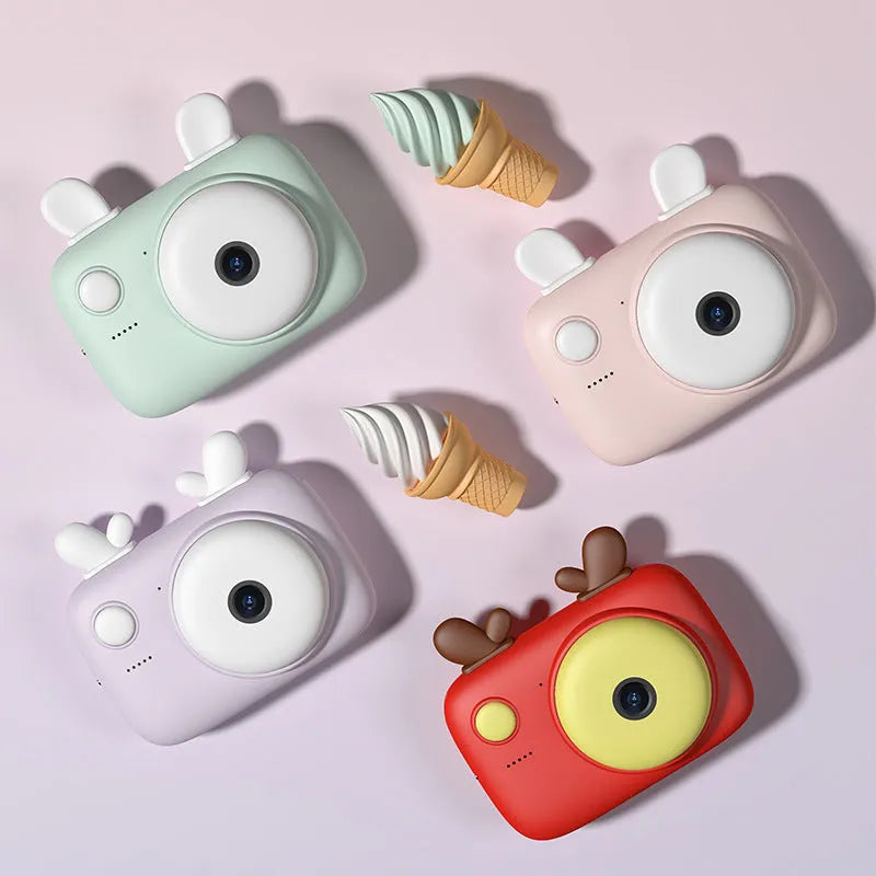 A2 Kids Photo Camera in macaron colours with 2.4-inch screen, dual lenses, and attached lanyard.