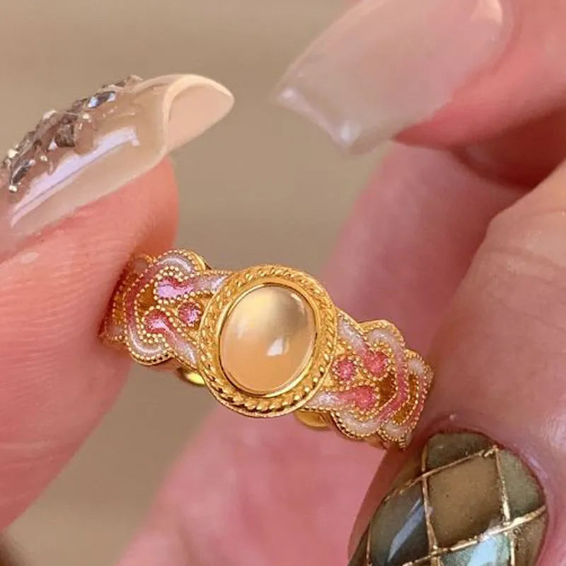Geometric open ring for women with pink crystal enamel decoration on a gold-toned band.