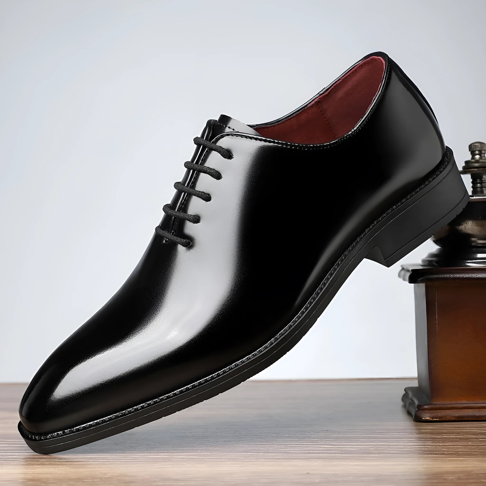 Men's glossy pointed toe business shoes in black with artificial PU upper and rubber sole on a brightly lit surface