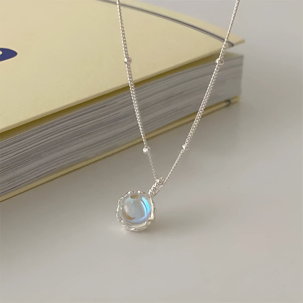 Women's silver necklace with large round geometric stone pendant on a curb chain.