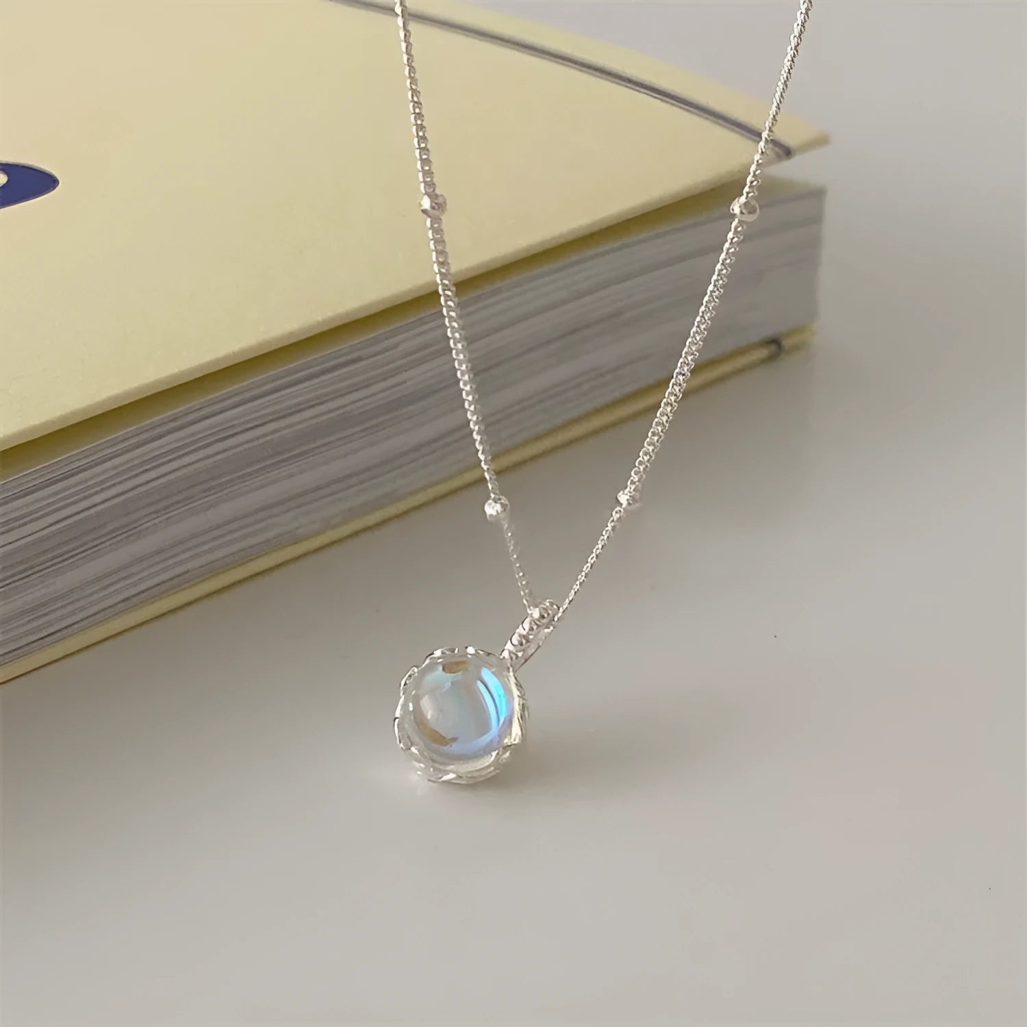 Women's silver necklace with large round geometric stone pendant on a curb chain.