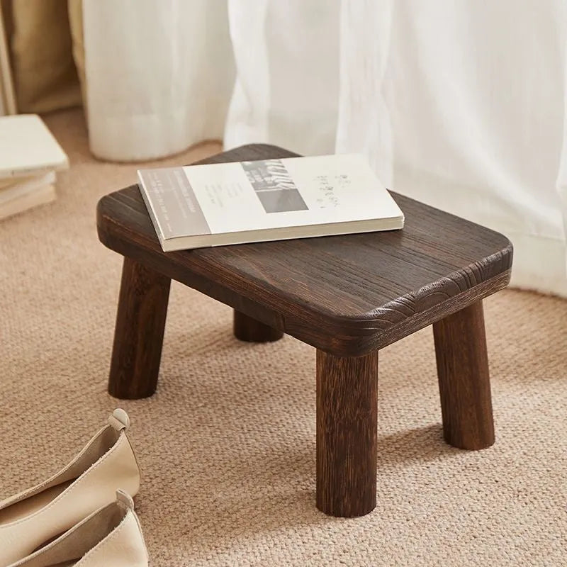 Solid wooden shoes changing stool with a distressed finish and bracket leg structure.