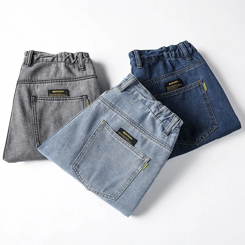 Men's loose straight-cut blue jeans on a plain background, showing the mid waist and zipper fly detail.
