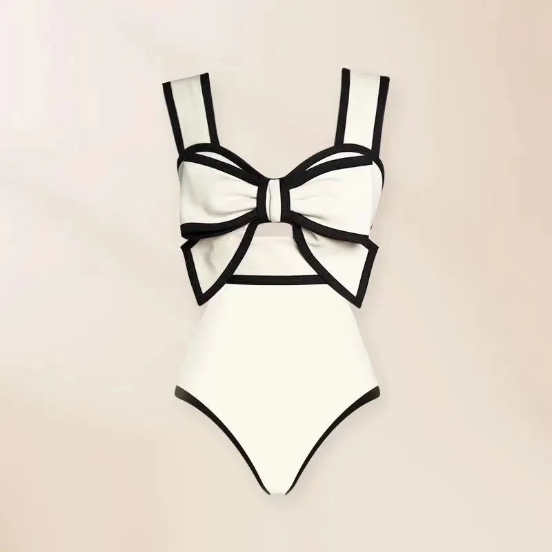 Women's black one-piece swimsuit with attached beach dress skirt featuring bow detail