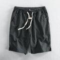 Man wearing striped casual cotton shorts with a loose straight fit and mid waist, showcasing the micro elastic fabric.