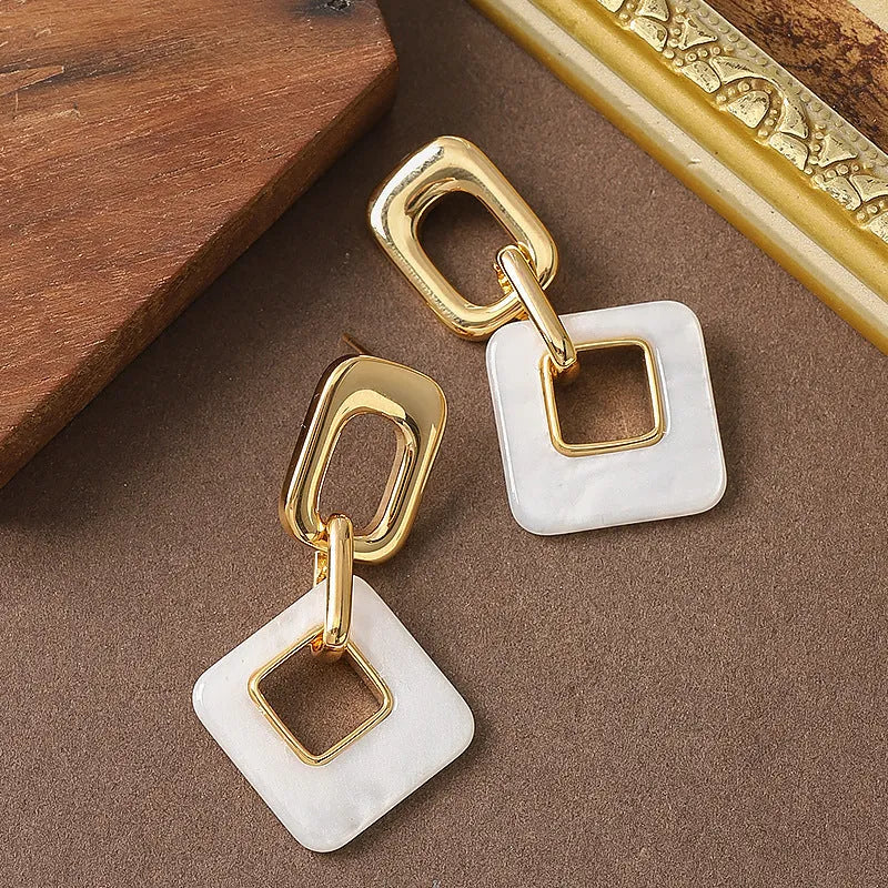 A pair of hollow geometric square earrings with chamfered corners, made from electroplated copper.