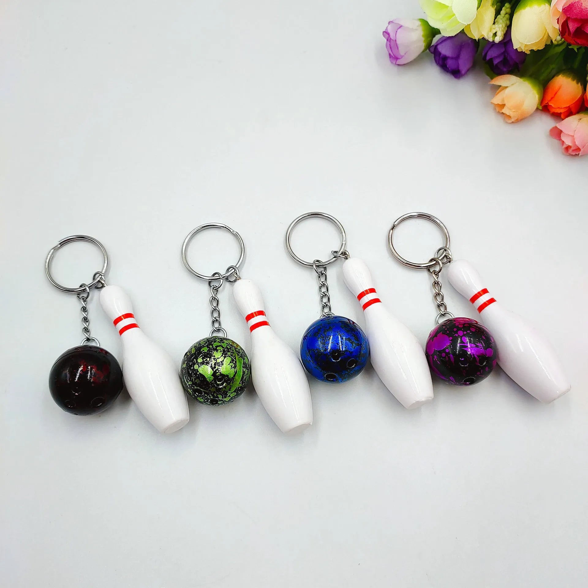 Mini bowling ball keychain pendant in PVC metal showing four colour options: dark red, blue, purple, green