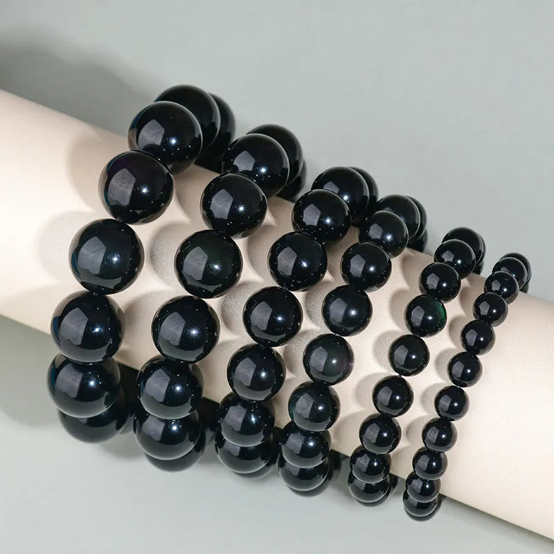 Hand-woven round obsidian bracelet with crystal beads in various colour options on a wrist.