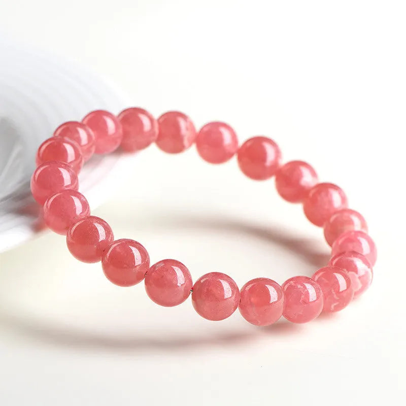 Women's geometric red rhodochrosite crystal bracelet with a longevity lock clasp on a wrist.