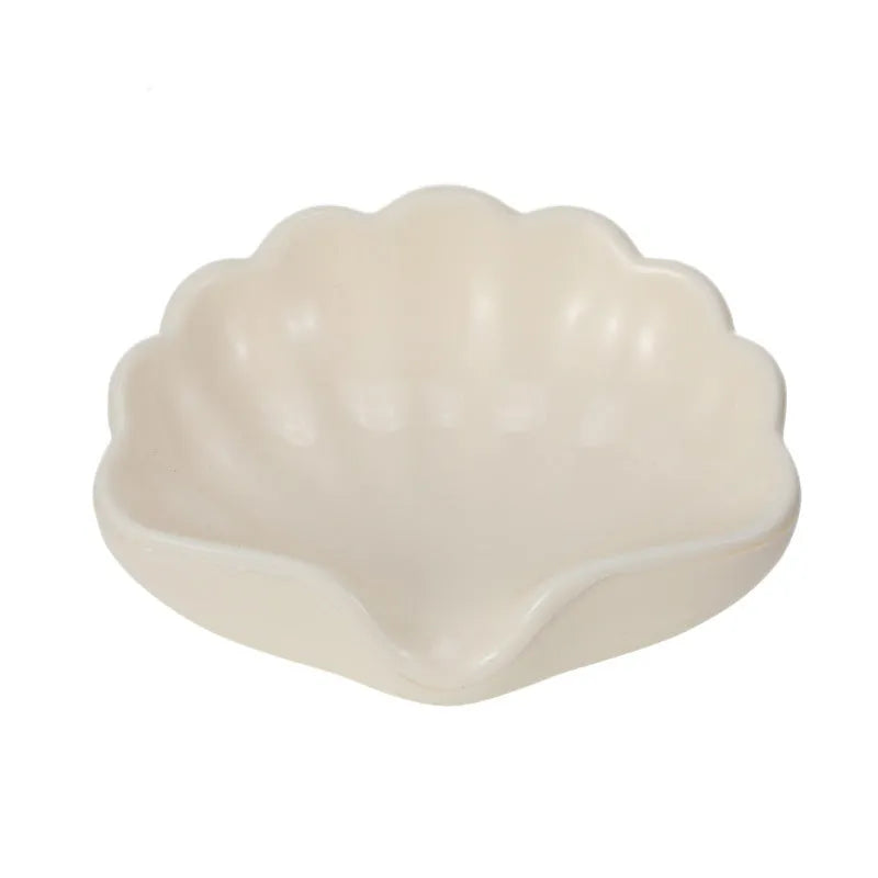 White plastic shell-shaped soap dish for bathroom countertop with soap bar on it.