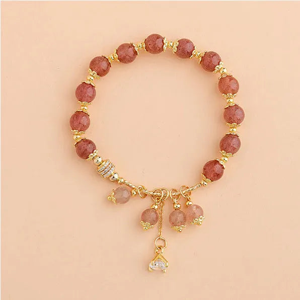 Pink heart-shaped strawberry quartz and pearl women's bracelet on a wrist.