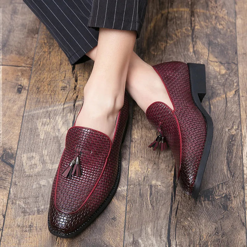 Men's black pointed toe slip-on shoes with a tassel detail on the front.