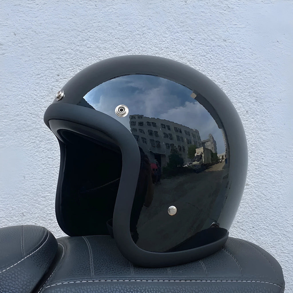 A retro-style motorcycle half helmet made from grey fibreglass, shown from the side.