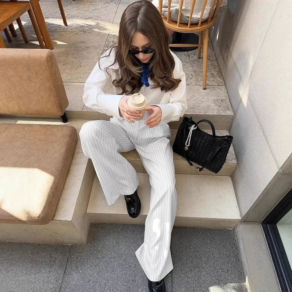 White striped wide-leg women's trousers with side zip, laid flat to show loose fit and pattern.