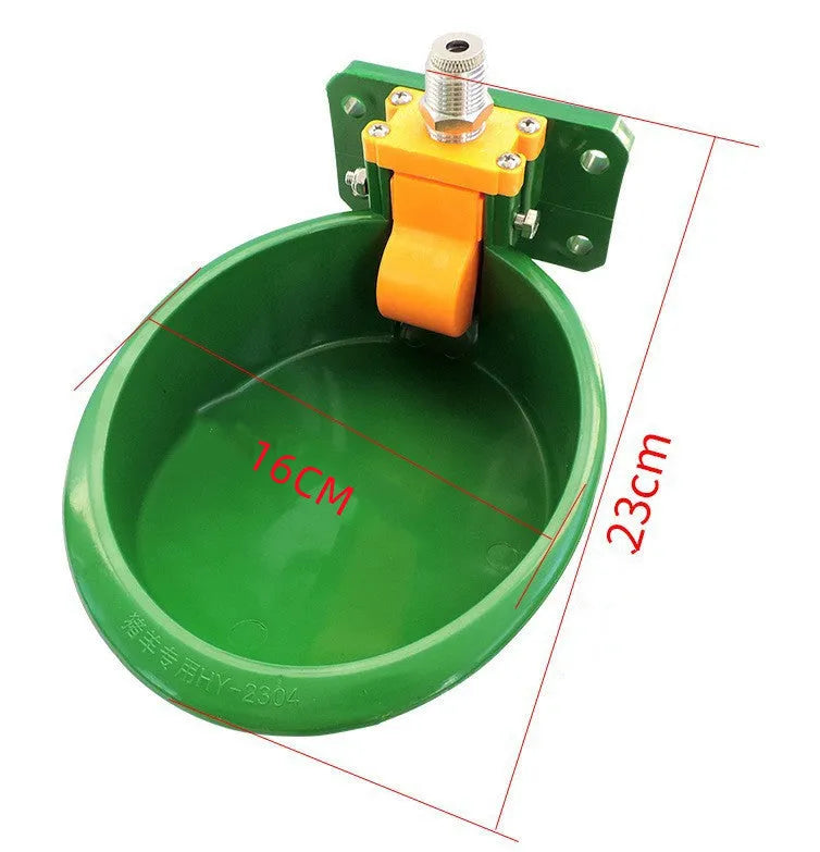 Green plastic automatic drinking bowl with nozzle for sheep and pigs on a farm.