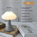 Mushroom-shaped touch control night light in cream colour on a wooden table.