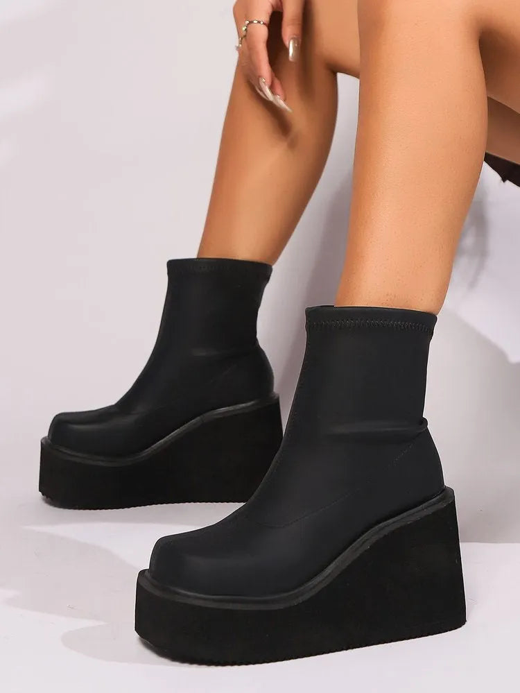 Plus size black artificial PU women's ankle boots with a wedge heel and round toe on a model.