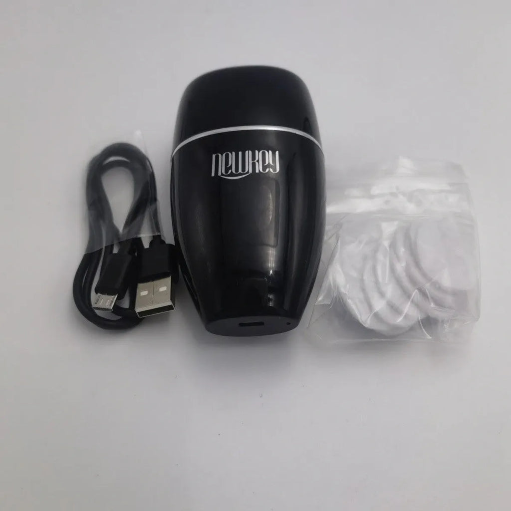 Black and white electric lip plumper device with silicone tip and USB cable on a plain background.