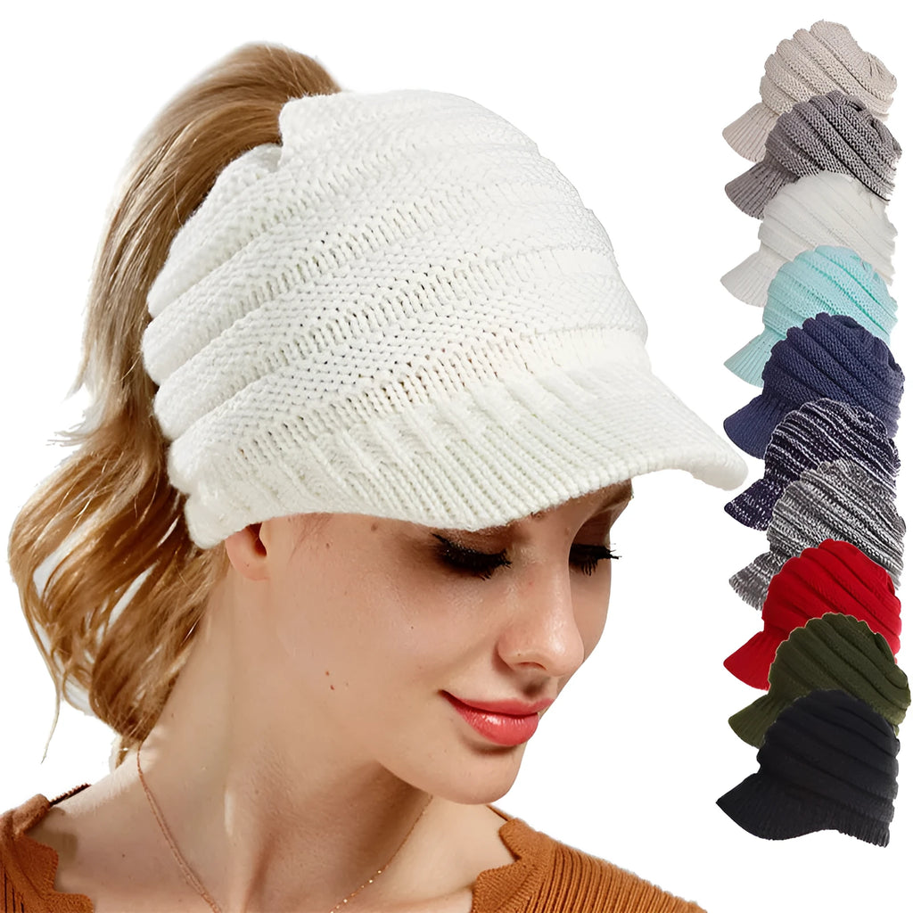 Woman wearing a light grey knitted beanie with a ponytail pulled through the back opening.