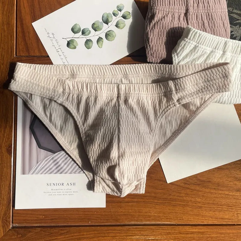 Men's solid colour cotton triangle underwear briefs laid flat, showing mid-waist design in apricot, black, skin colour and white options.