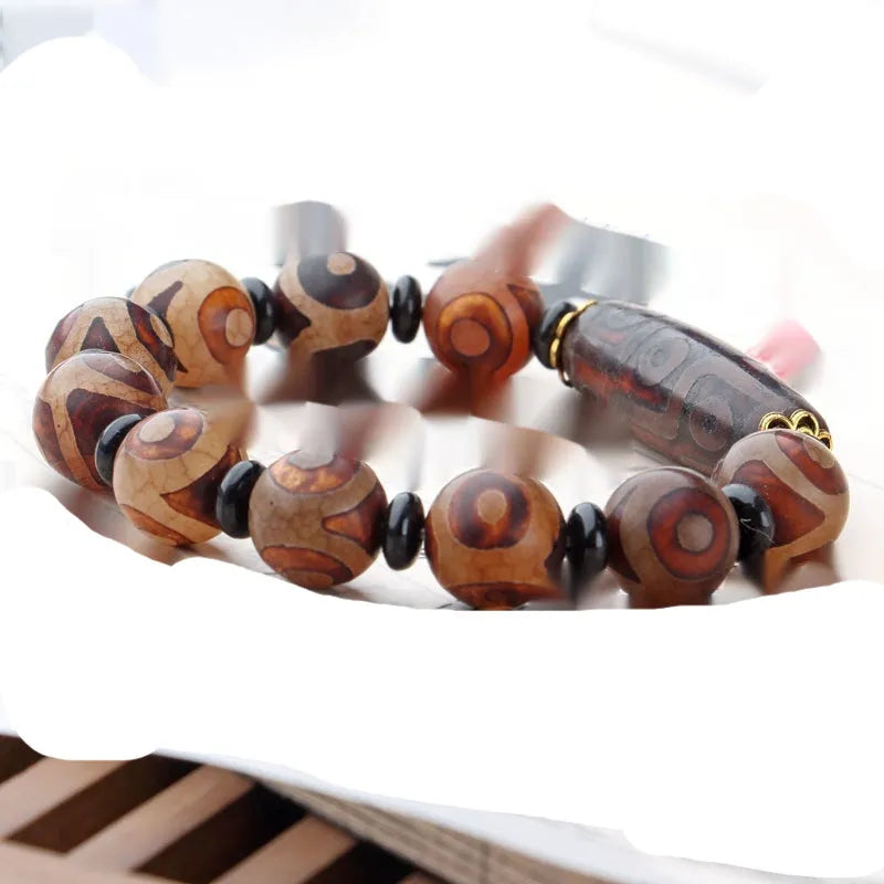 Distressed agate Tibet bead bracelet with three-eye motifs and multiple traditional bead styles on wrist