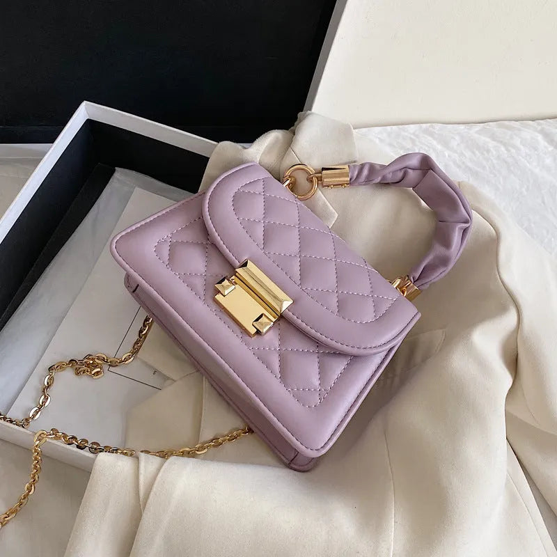Purple rhombus-shaped women's shoulder bag with crossbody strap on mannequin