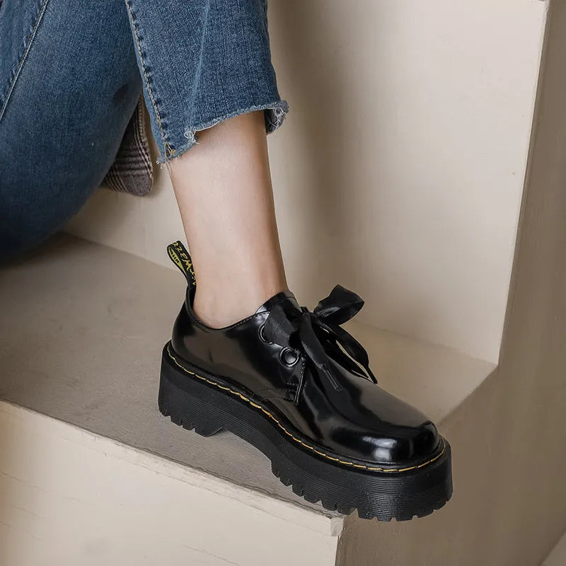 Women's thick soled leather shoes with ribbon cross straps and lace-up closure in black colour