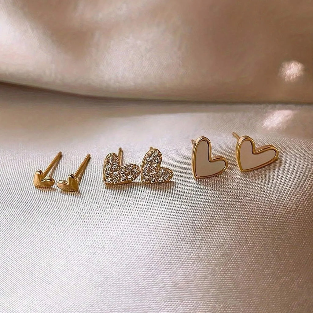 Three pairs of heart-shaped earrings in gold, black, pink, and black white colours with love-themed girly styling