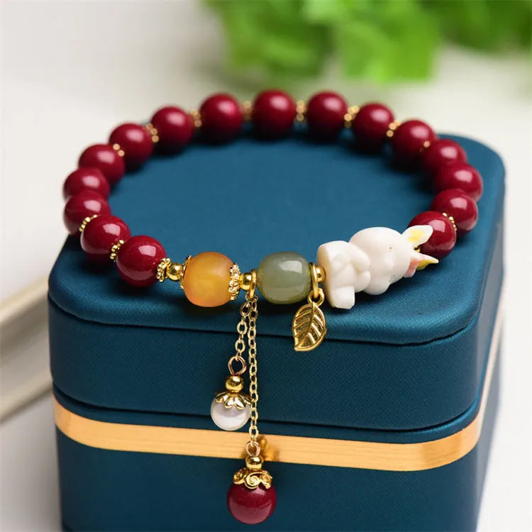 Women's natural cinnabar bracelet with a detailed rabbit pendant, shown in red.
