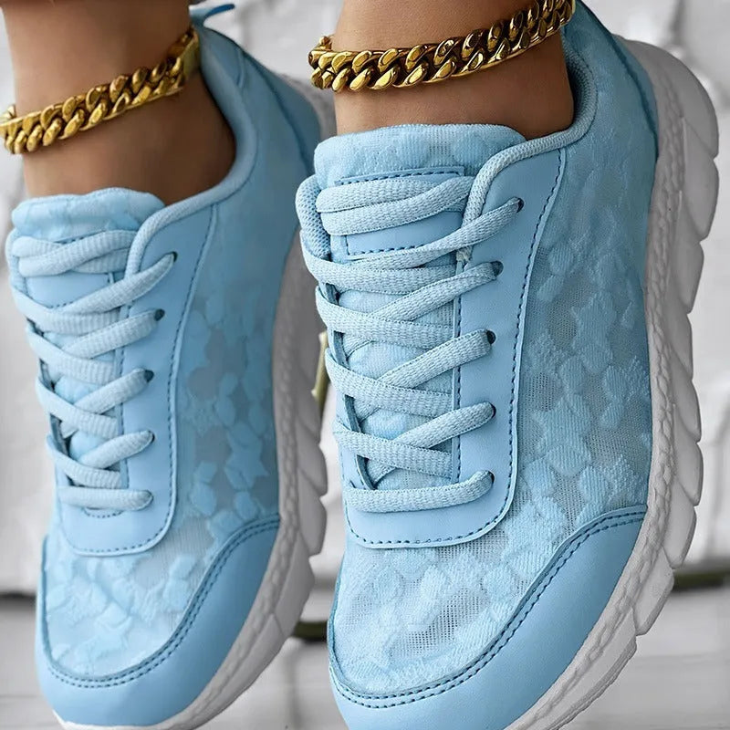 Women's white canvas running shoes with a flat sole and round toe on a neutral background.