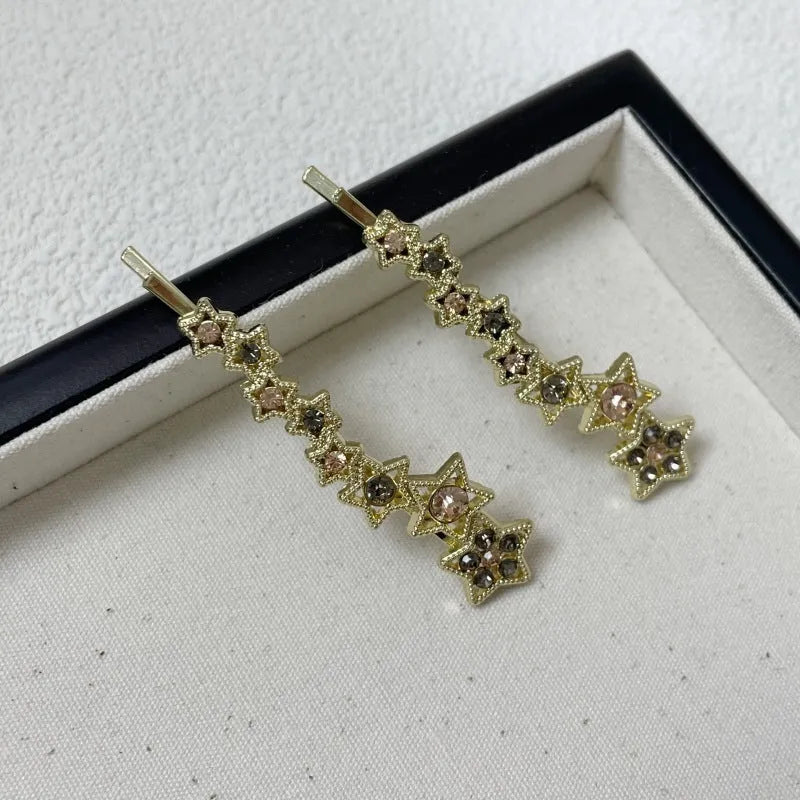 Golden hair clip barrette with a rhinestone five-pointed star, shown on a side angle.