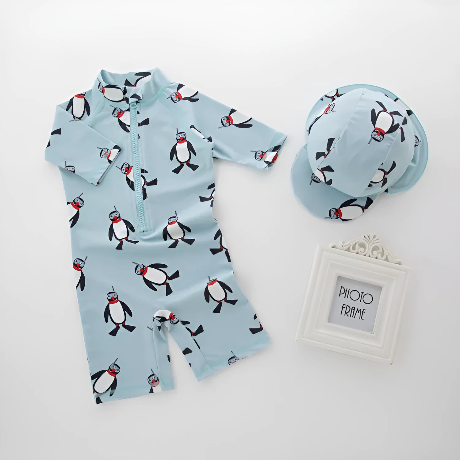 Boy's blue penguin print long sleeve swimsuit top and shorts with matching swimming cap.