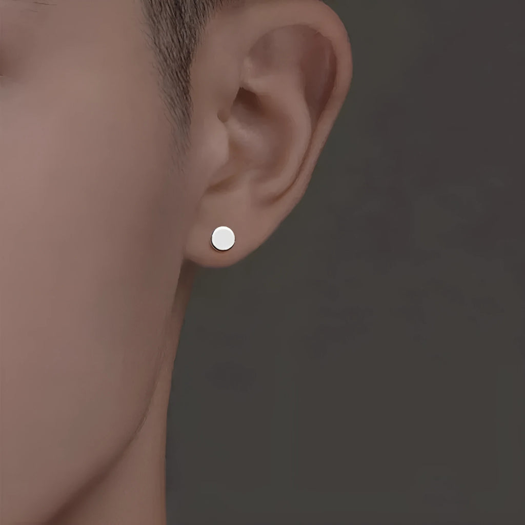 A pair of simple round flat-front sterling silver S999 ear bone stud earrings on a plain background.